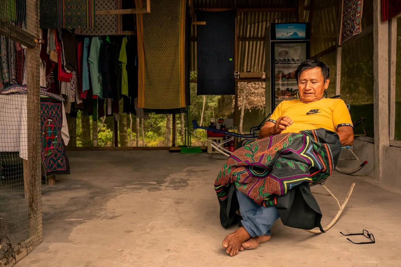Maestro Miguel Muñoz embroidering a kené cloth in a rocking chair